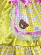 Yellow dress with pink trim, lace, and a teddy bear patch.