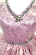Close-up of a pink dress with sparkling embellishments on a light pink background