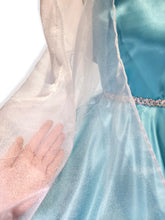 Close-up of a light blue satin dress with a hand for scale