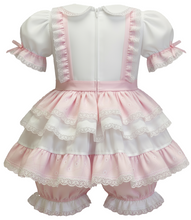 Pink and white baby outfit with ruffled top and bloomers on a white background