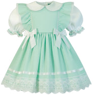 A mint green and white adult baby girl's dress featuring a Peter Pan collar, ruffled puff sleeves, white satin bows at the waist, and a lace hem.