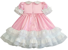 A pink and white adult baby girl's dress with a satin-like pink bodice, white lace collar, ruffled short sleeves, and a tiered white lace skirt.