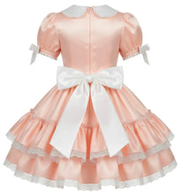 A peach satin dress with a white Peter Pan collar, short puff sleeves with white ribbon bows, and a large white bow at the back of the waist, shown against a plain white background.