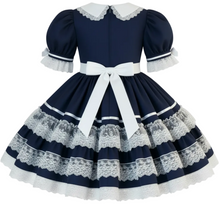 A navy blue and white Lolita-style dress with puffed short sleeves, a white collar, a large white waist bow, and layered white lace ruffles on the skirt, shown against a plain white background.
