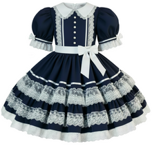 A navy blue and white Lolita-style dress with puffed short sleeves, a white collar, lace trim, a white waistband with a bow, and a tiered skirt with lace bands.
