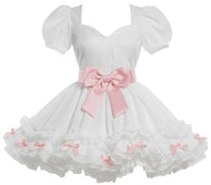 White baby girl's dress with puff sleeves, a sweetheart neckline, a large pink ribbon bow at the waist, and a layered ruffled skirt with small pink bows, displayed on a mannequin.