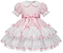 A pink and white adult baby girl's dress featuring a short puff sleeve, a white Peter Pan collar, a pink waist bow, and a tiered ruffled skirt with pink trim.