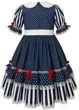 A navy blue and white polka dot and striped dress. The dress features a white Peter Pan collar, short puff sleeves with red ribbon bows, and a tiered skirt with red bows and white lace trim.