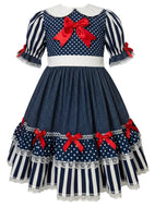 A navy blue and white polka dot and striped dress with red bows, featuring a white Peter Pan collar and short puff sleeves with lace trim.