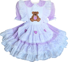 A custom fit eyelet teddy bear hearts ruffles adult sissy dress with a Peter Pan collar, white eyelet bodice ruffles, elasticized puff sleeves, a ruffled skirt with white eyelet ruffles, and lace and heart appliques. The dress features a front apron skirt, a back zipper closure, and is displayed over a mini hoop skirt which is not included.