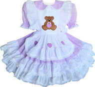A custom fit eyelet teddy bear hearts ruffles adult sissy dress with a Peter Pan collar, white eyelet bodice ruffles, elasticized puff sleeves, a ruffled skirt with white eyelet ruffles, and lace and heart appliques. The dress features a front apron skirt, a back zipper closure, and is displayed over a mini hoop skirt which is not included.