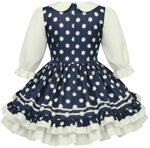 Navy blue dress with white polka dots and a large white bow on a white background