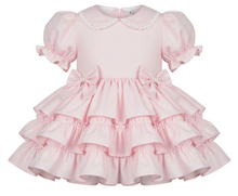 Pink dress with ruffled layers on a white background